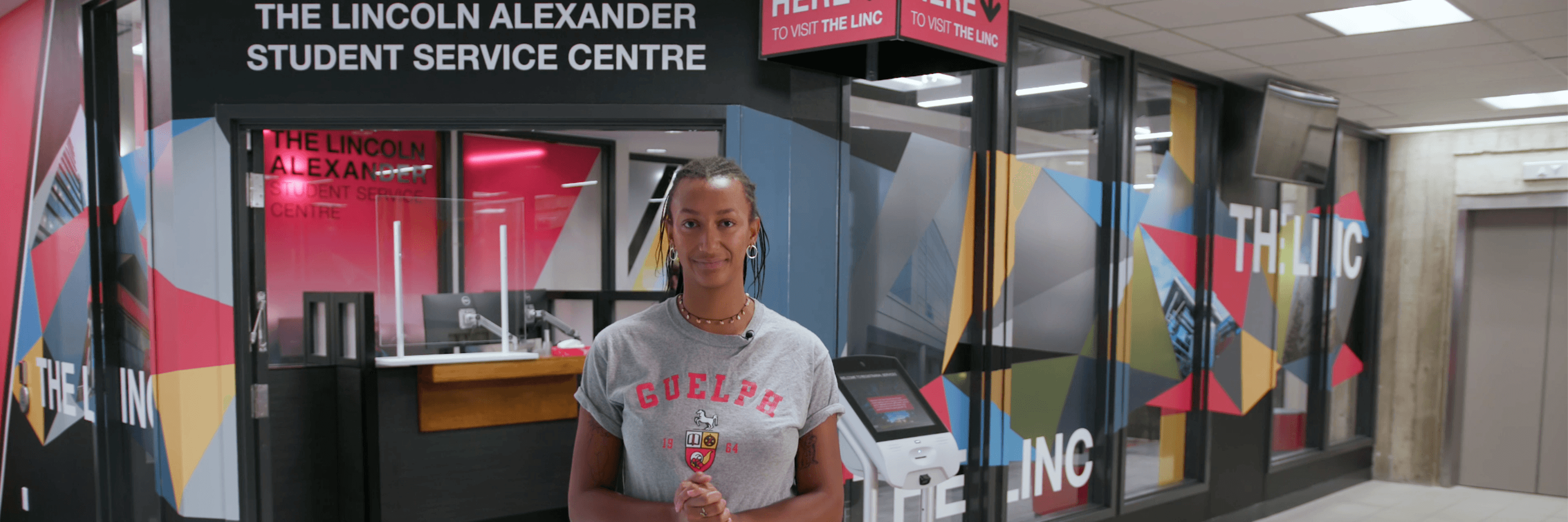 Student standing in front of doors to the Lincoln Alexander Student Service Centre
