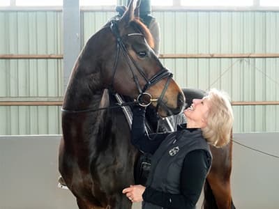 Middle-aged woman looking eye-to-eye with her horse.