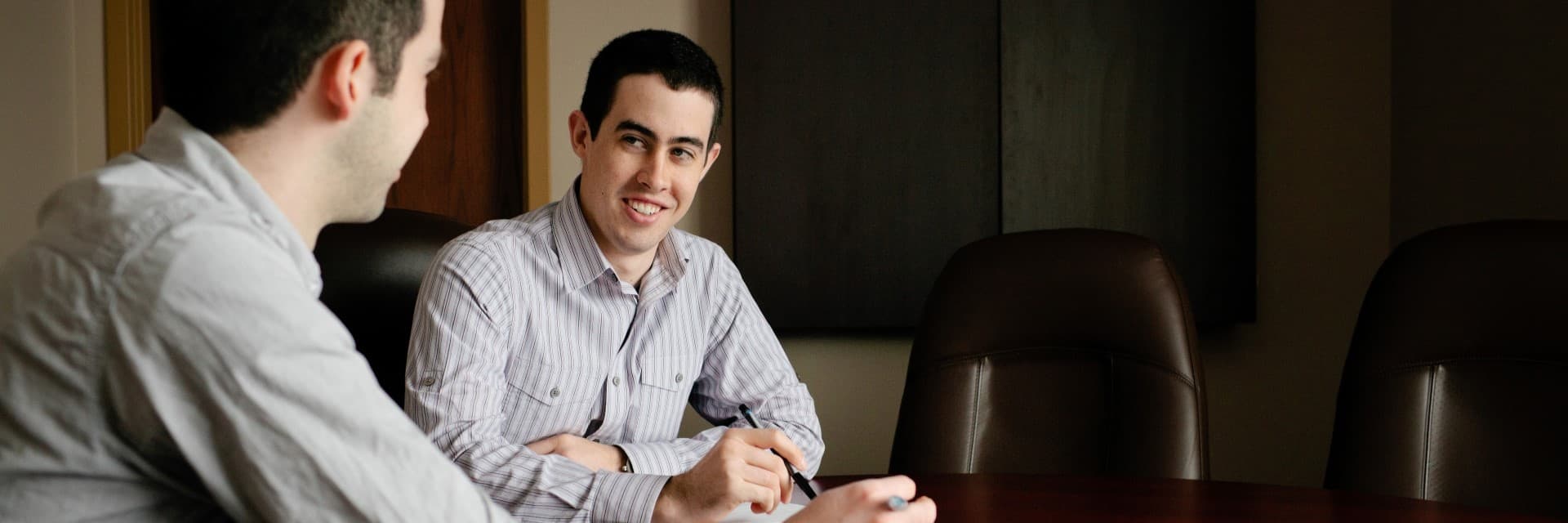 Two people in conversation at a board room table in an office.