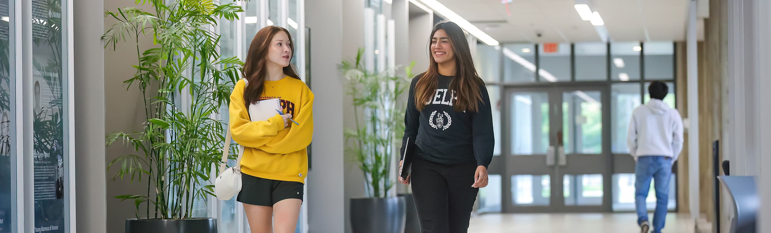 Two students walk together while chatting and laughing in the engineering building.