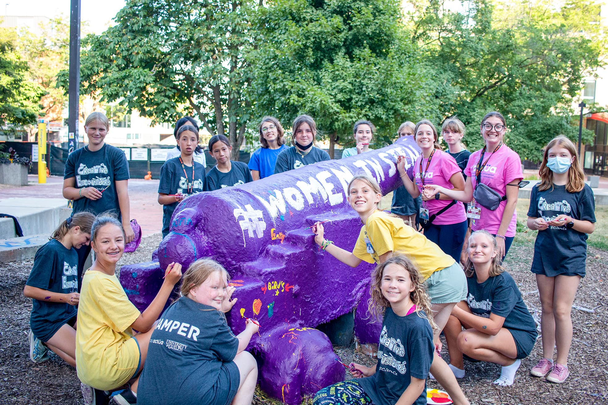 High school students painting "#Women In STEM" on cannon at the University of Guelph