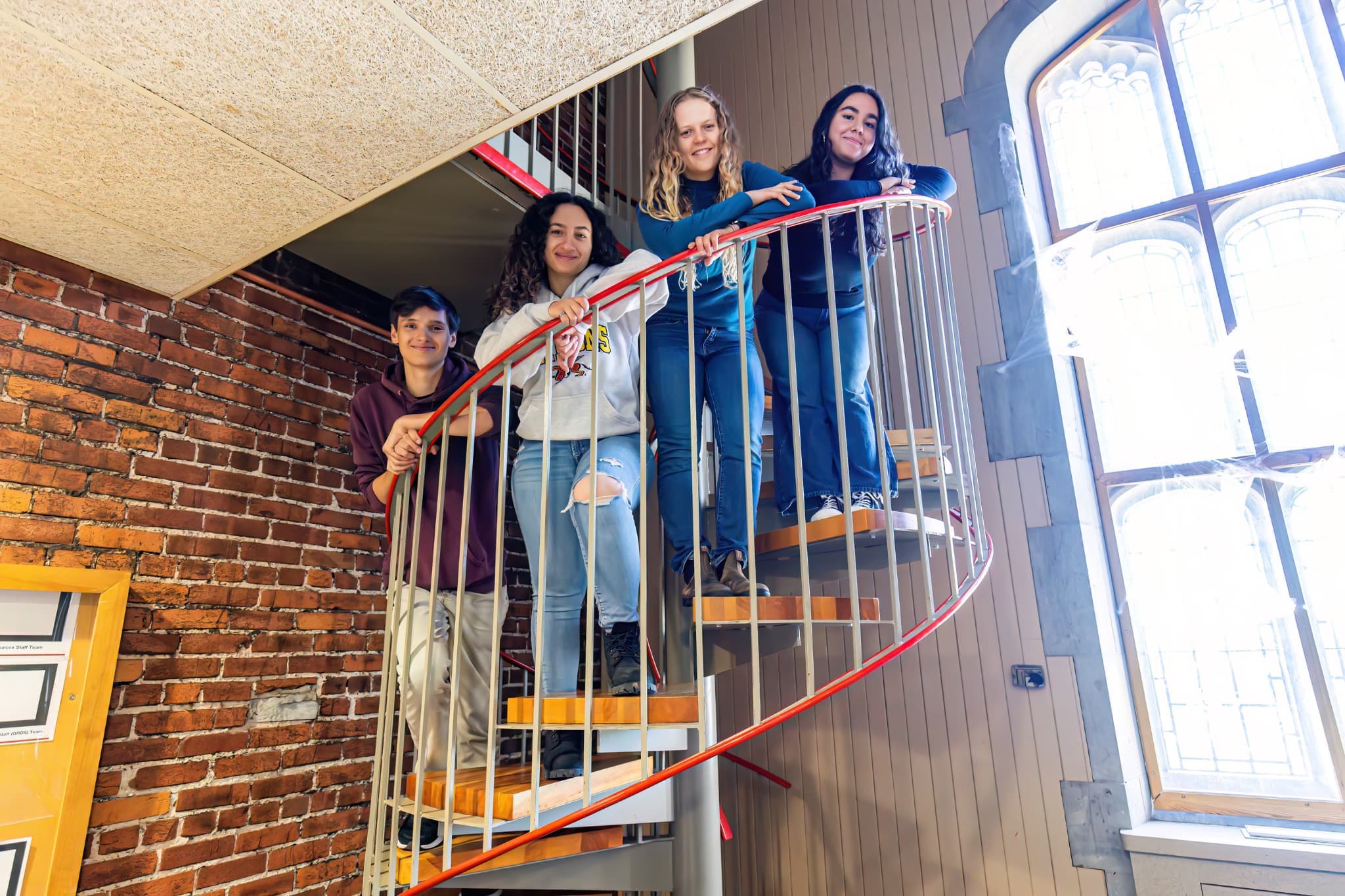 Four students standing around the staircase in Johnston Lounge