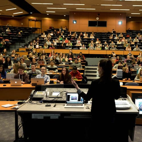 A professor lecturing in front of a class of students.